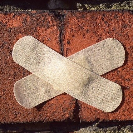 Two plasters stuck in a cross over a crack in a brick wall